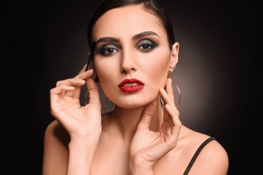 Siyah arka planda güzel makyajlı genç bir kadın.