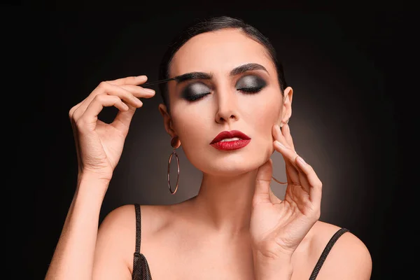 Mulher Bonita Aplicando Maquiagem Contra Fundo Escuro — Fotografia de Stock