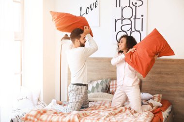 Yatak odasında yastıklarda kavga eden mutlu genç çift.