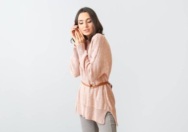 Hafif arka planda kalın süveter giyen güzel bir kadın.