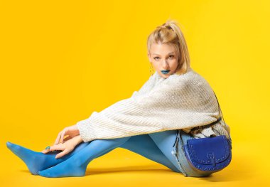 Yaratıcı makyajlı ve arka planda kalın kazaklı genç bir kadın.