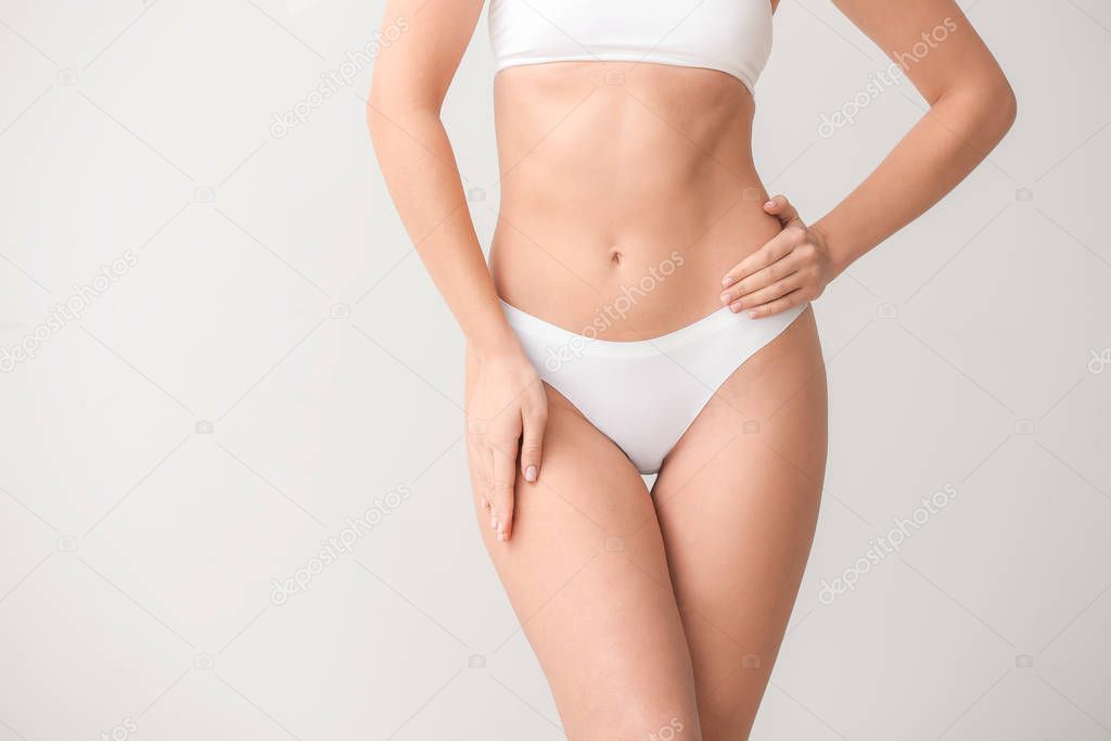 Beautiful young woman in underwear on light background. Concept of plastic surgery
