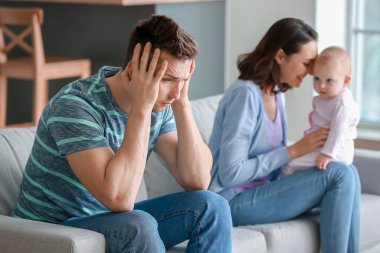 Bebeğiyle mutlu bir anne ve evde doğum sonrası depresyon geçiren genç bir baba.