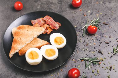 Kaynamış yumurta, pastırma ve koyu arkaplanda kızarmış ekmek.