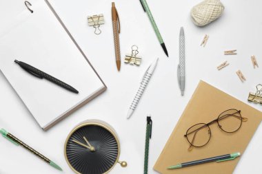 Beyaz arka planda saati olan okul malzemeleri.