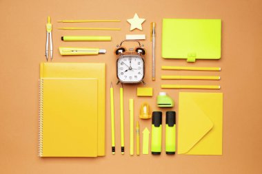 Renkli arkaplan üzerinde saati olan okul gereçleri