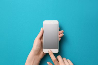 Renkli arka planda cep telefonu olan kadın elleri