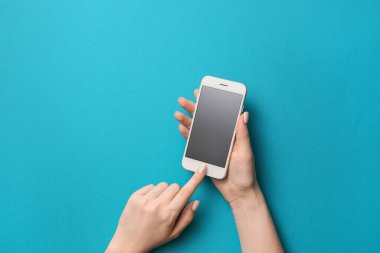 Renkli arka planda cep telefonu olan kadın elleri