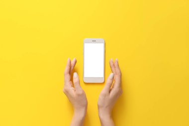 Renkli arka planda cep telefonu olan kadın elleri