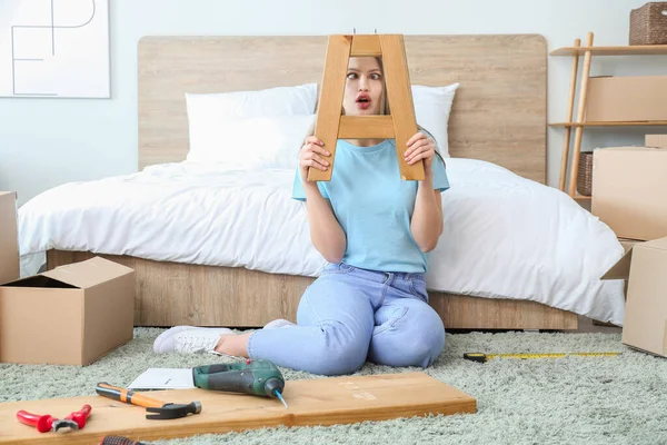 Emotional woman assembling furniture at home