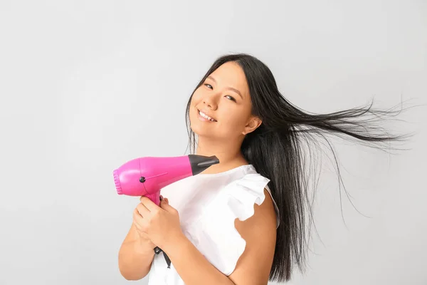 Schöne Asiatische Frau Mit Haartrockner Auf Hellem Hintergrund — Stockfoto