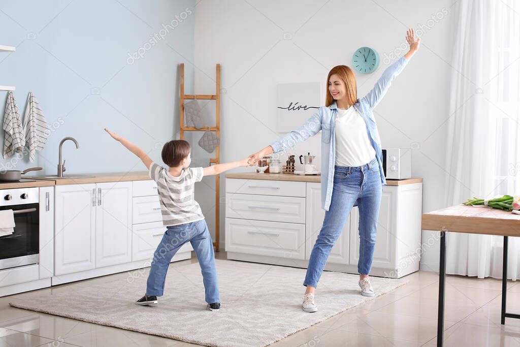 Happy mother and her little son dancing in kitchen