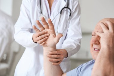 Klinikte Parkinson sendromu olan yaşlı bir adamla çalışan kadın doktor.