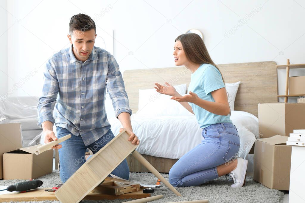 Emotional couple assembling furniture at home