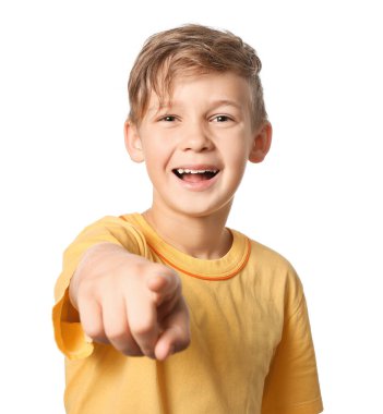 Küçük mutlu çocuk beyaz arka plandaki izleyiciyi işaret ediyor.