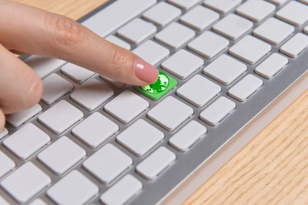 Woman pressing key with drawing of planet on PC keyboard. Earth Day celebration