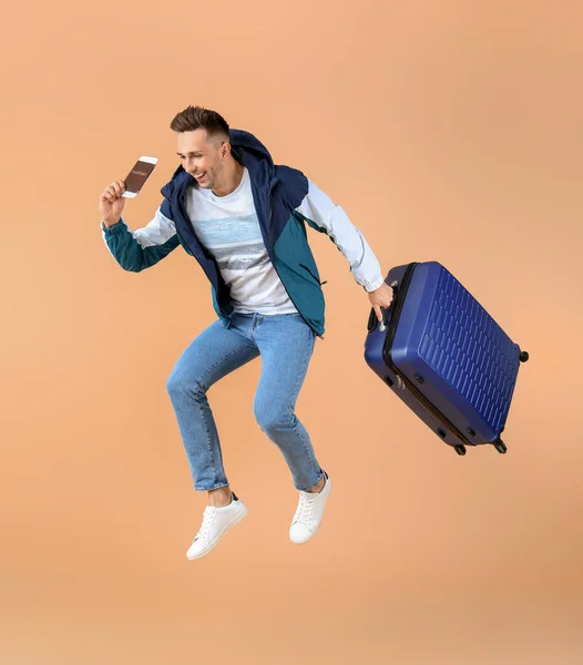 Springender Männlicher Tourist Mit Gepäck Auf Farbigem Hintergrund — Stockfoto