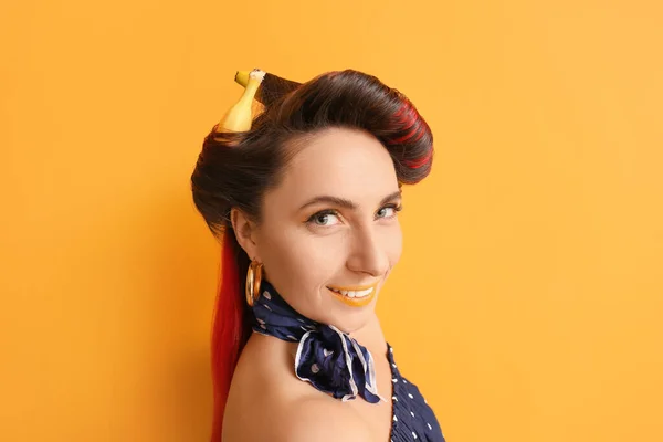 Beautiful woman with bananas in her hair on color background