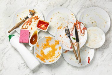 Açık arkaplanda kirli boş sofra takımı ve deterjan