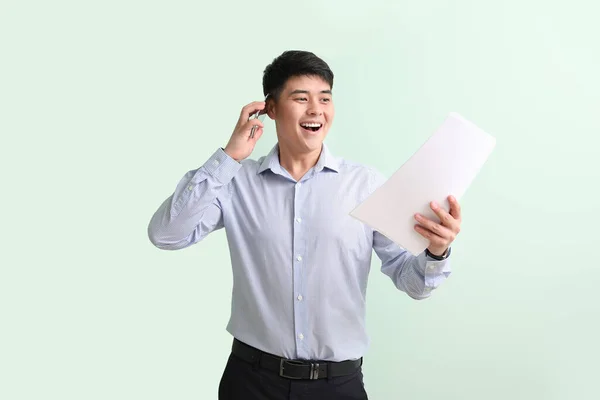 携帯電話と色の背景に文書を持つ幸せな若いアジアのビジネスマン — ストック写真
