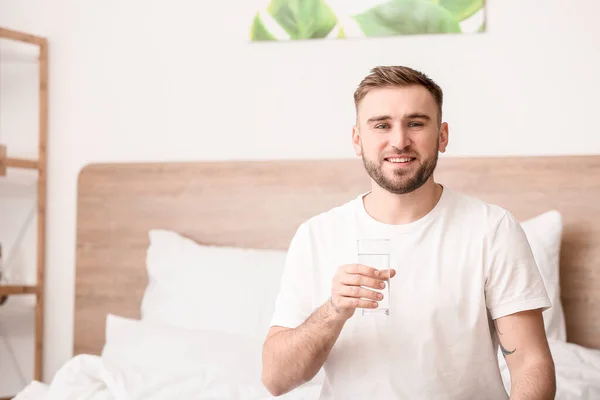 Morning of young man drinking water in bedroom