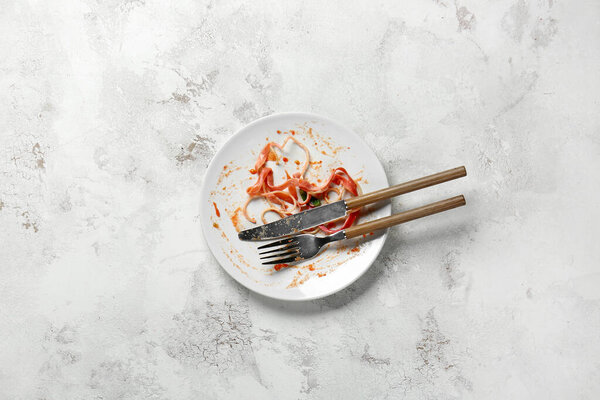 Dirty empty plate with cutlery on light background