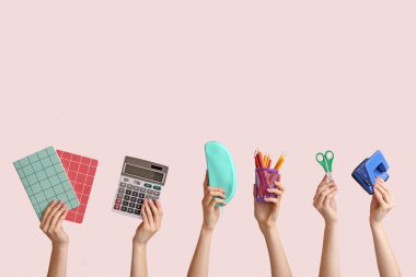 Arka planda okul malzemesi olan bir sürü el var.