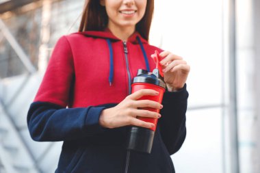 Dışarıda protein içeceği içen genç sporcu kadın.