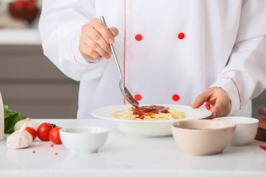 Kadın aşçı mutfakta domates soslu lezzetli makarna pişiriyor.