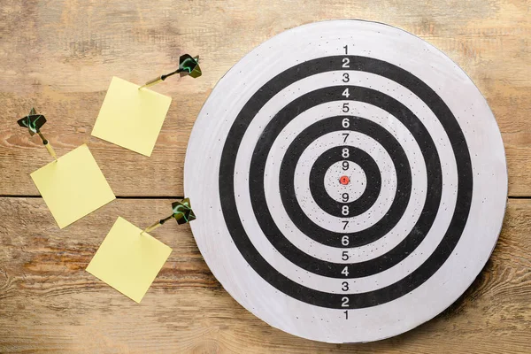 Dartscheibe Mit Darts Und Papierblättern Auf Holzgrund — Stockfoto