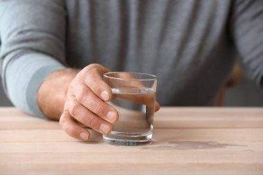 Parkinson sendromlu yaşlı adam evinde su içiyor, yakın plan.