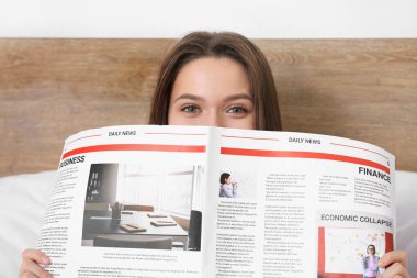 Morning of beautiful young woman reading newspaper in bed