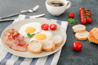 Koyu arkaplanda kızarmış yumurta, pastırma ve ekmek var.