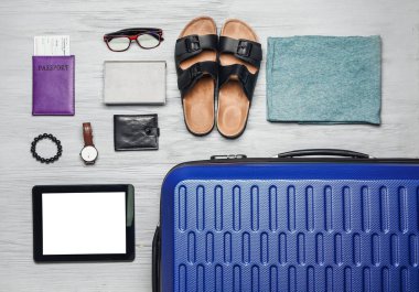 Ahşap arka planda aksesuar, bavul ve tablet bilgisayarlı şık erkek giysileri.