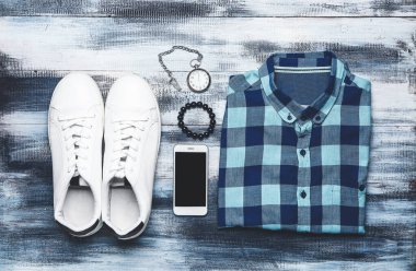 Aksesuar ve ahşap arka plan üstünde hareket eden telefon ile şık erkek giyimi