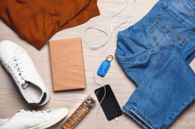 Aksesuar ve ahşap arka plan üstünde hareket eden telefon ile şık erkek giyimi