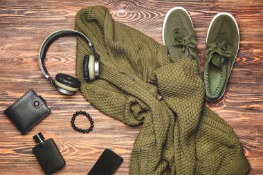 Ahşap arka planda aksesuarları ve cihazları olan şık erkek kıyafetleri.