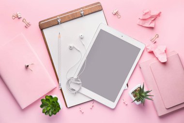 Pembe arka planda kırtasiye malzemesi olan tablet bilgisayarı