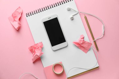 Pembe arka planda kırtasiye malzemesi olan cep telefonu