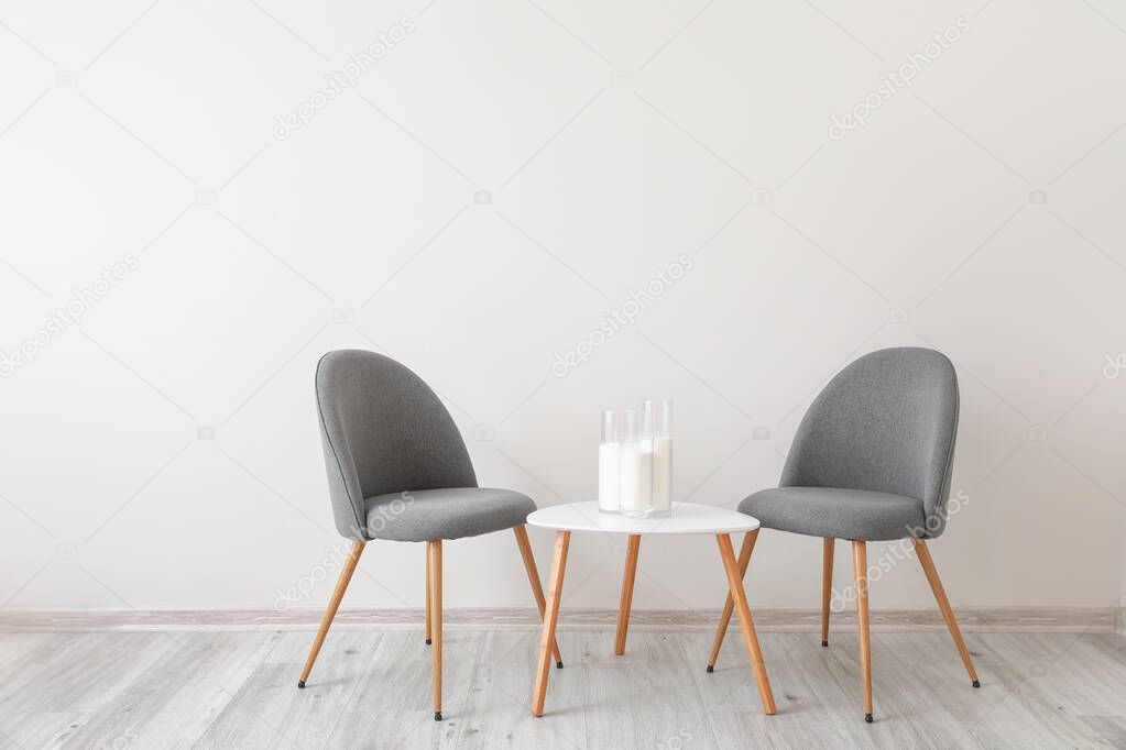 Chairs with table near white wall in room