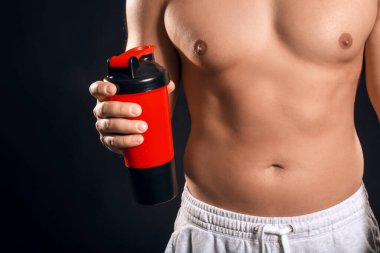 Siyah arka planda protein içeceği olan sportif adam, yakın plan.