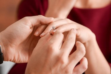 Genç adam yüzüğü nişanlısına parmağında sonra evlenme teklifi, closeup koyarak.