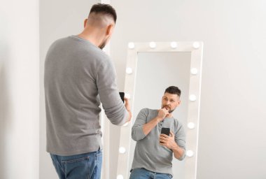 Yakışıklı adam aynanın yanında selfie çekiyor.