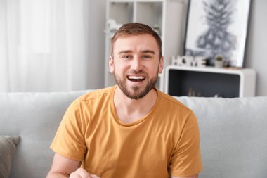 Genç adam evde görüntülü konuşma yapıyor.