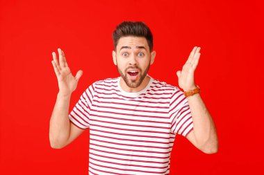 Renkli arka planda yakışıklı, şaşırmış genç bir adam.