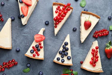 Gri arkaplanda farklı böğürtlenli tatlı, lezzetli peynirli kek parçaları.