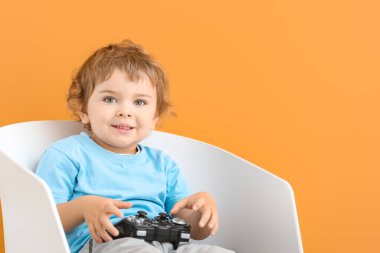 Oyun platformu olan şirin bir çocuk, renkli arka planda sandalyede oturuyor.