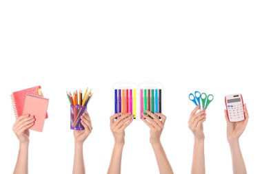 Beyaz arka planda okul malzemesi olan bir sürü el.