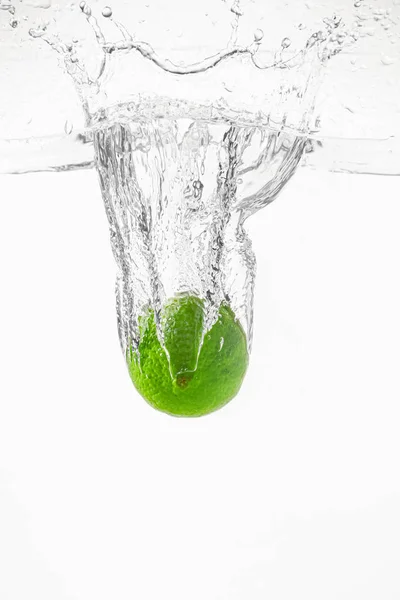 Falling of fresh lime into water against white background