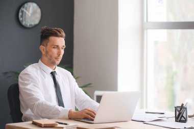 Ofiste Dizüstü bilgisayarda çalışan genç iş adamı.
